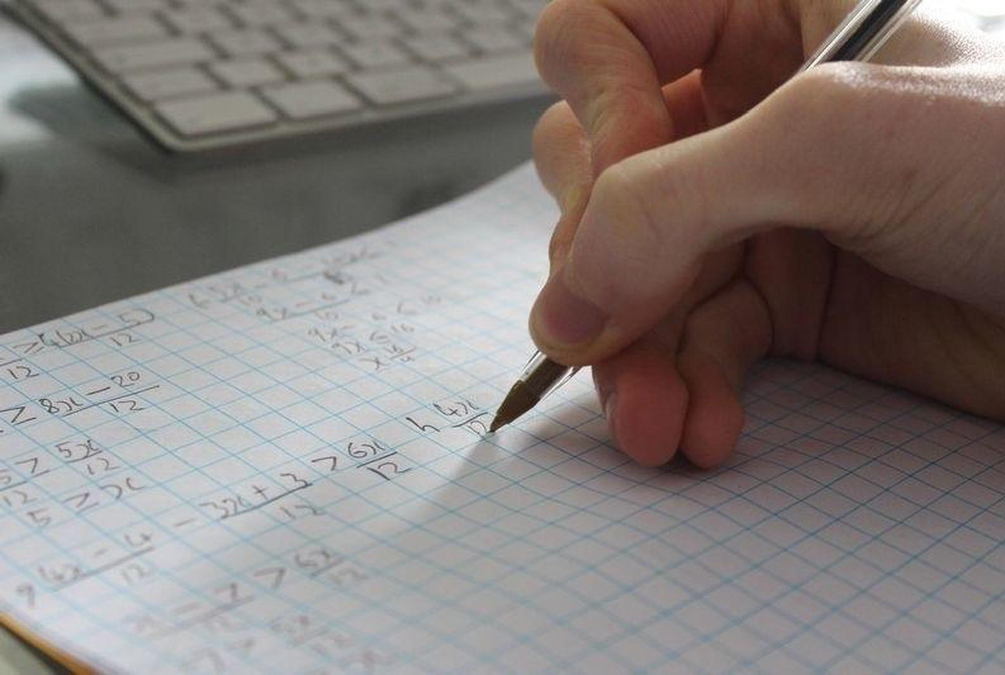 Maths Tutor Lessons Brent A person writing out mathematical equations representing Maths Tutor Lessons Willesden
